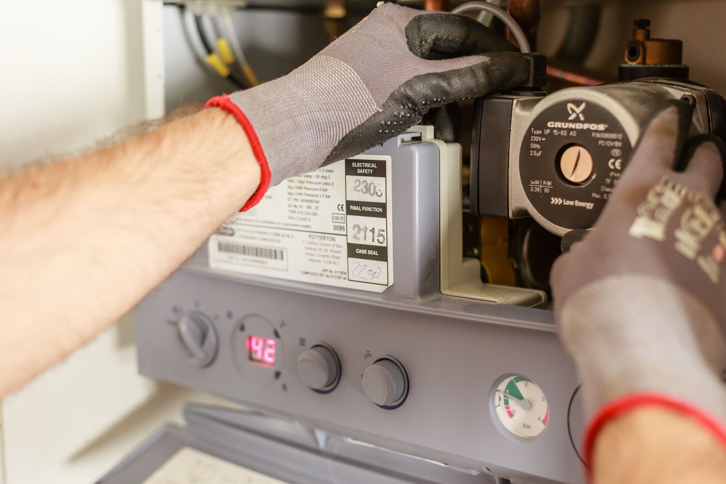 Handwerker mit Arbeitshandschuhen stellt eine Heizungsanlage ein